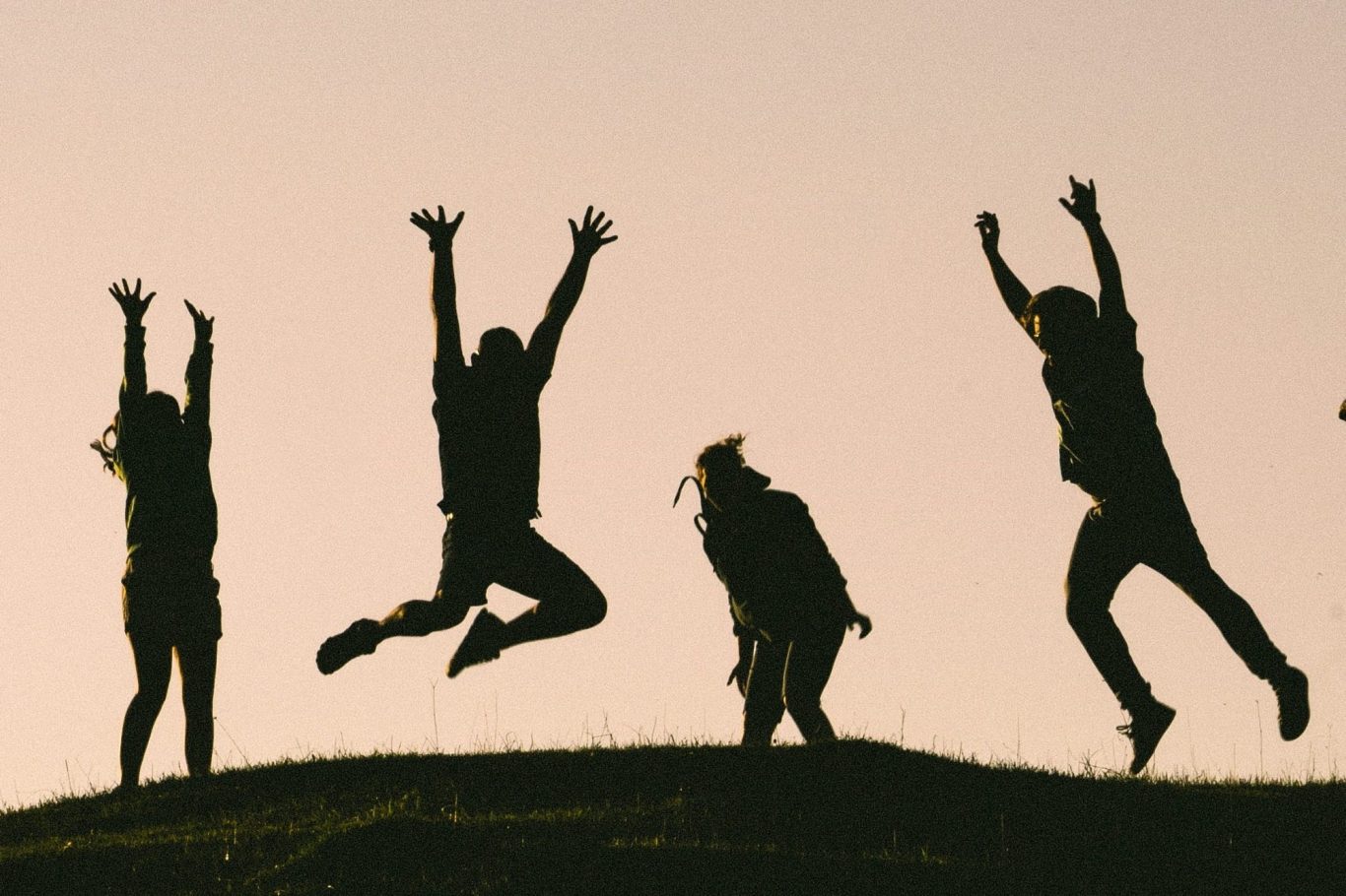 Ausdruckstanz Vier Tänzer auf einer Wiese tanzen ausdrucksstark mit ausladenden Bewegungen und machen Luftsprünge.